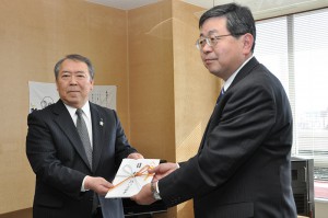 補助教材の目録を高橋教育長に手渡す松本理事長（左）