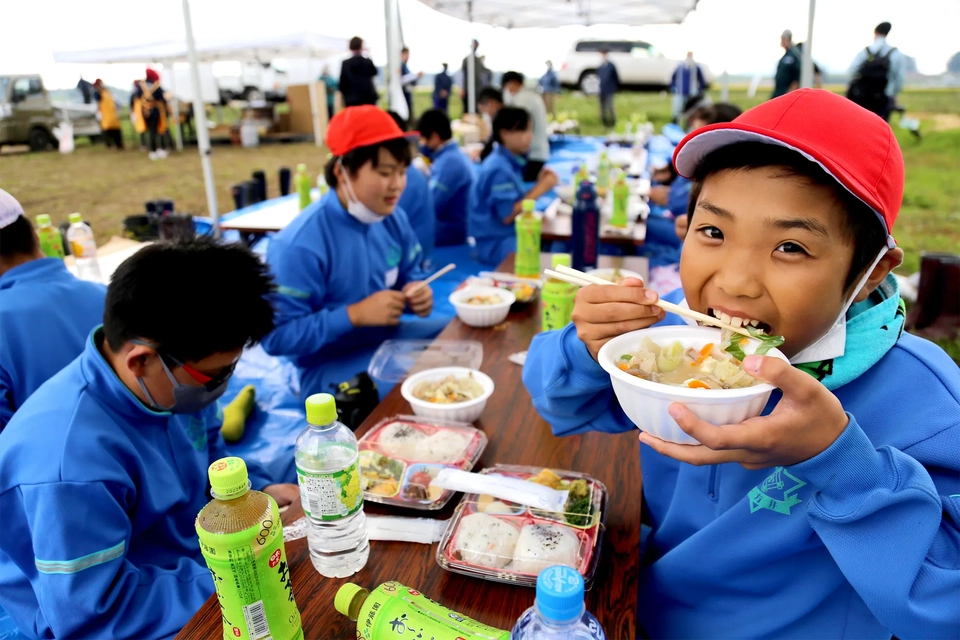 振る舞われた昼食に喜ぶ小学生たちの様子写真